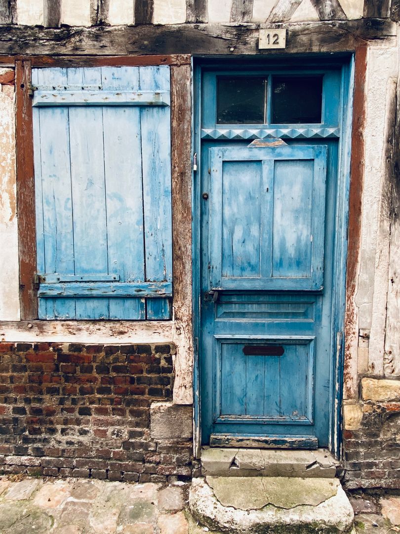 A blue door with shutters on an old building.