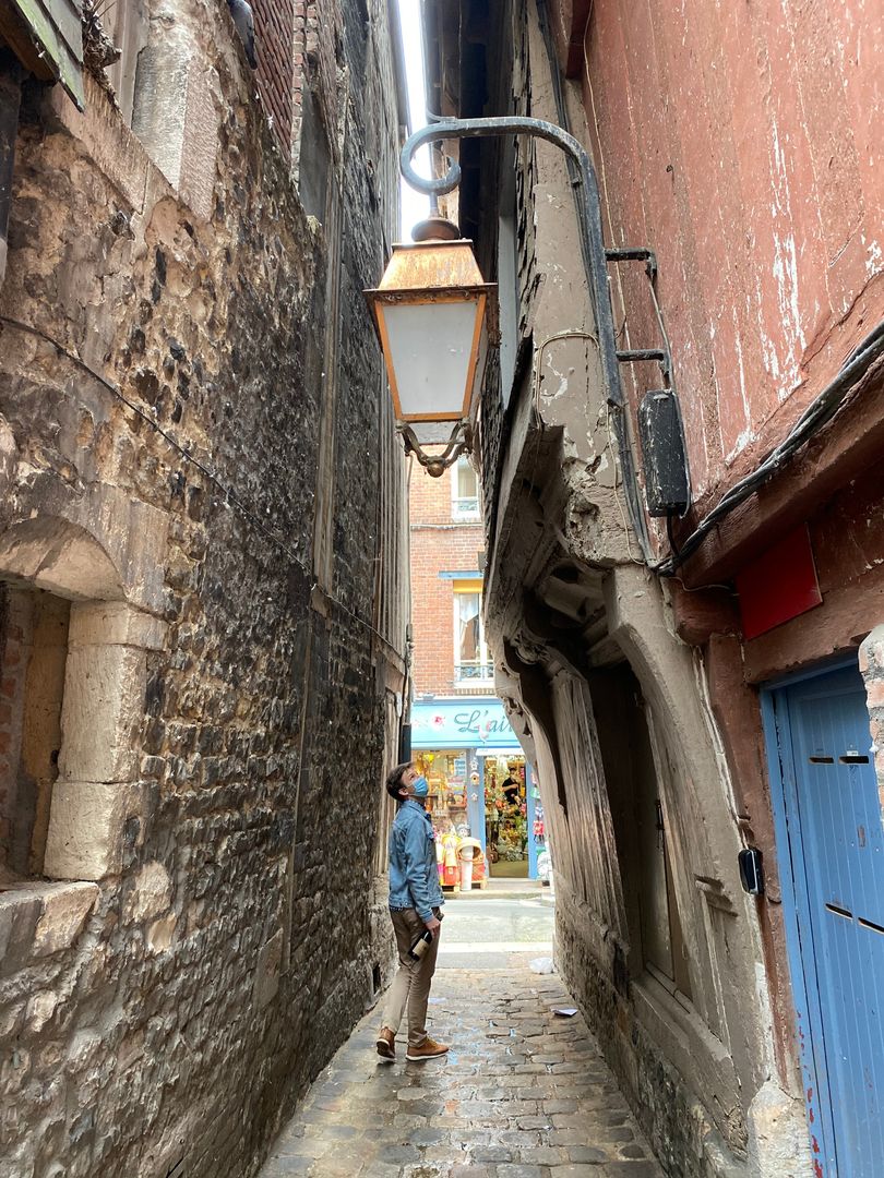 A man walking down a narrow alley in a city.