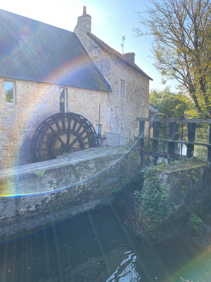 A water wheel in front of a stone building.
