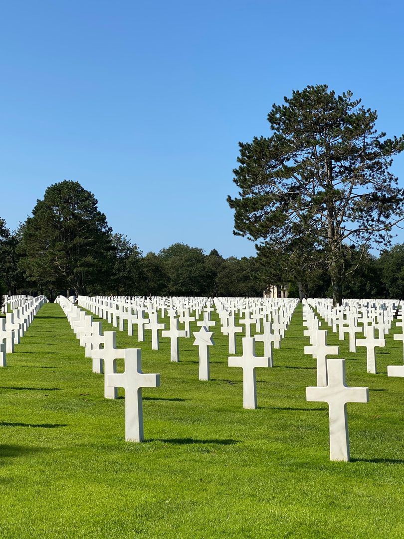A cemetery with many white crosses in the grass.