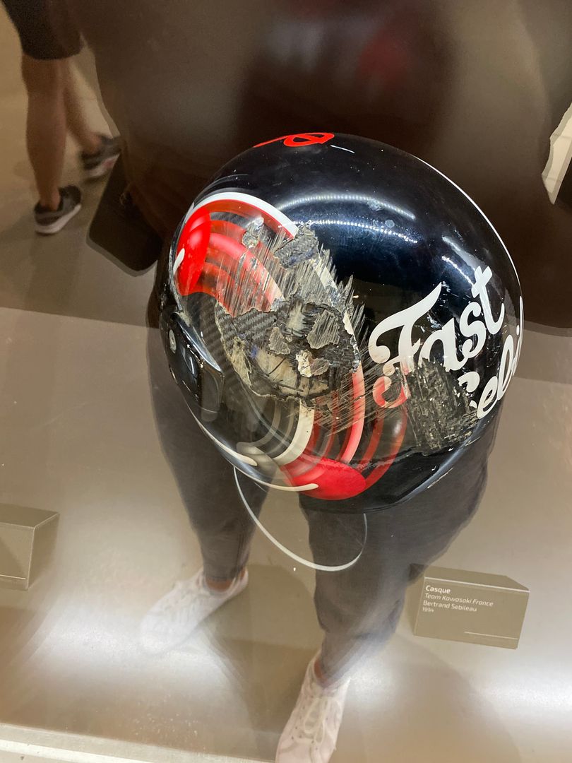 A motorcycle helmet is on display in a glass case.
