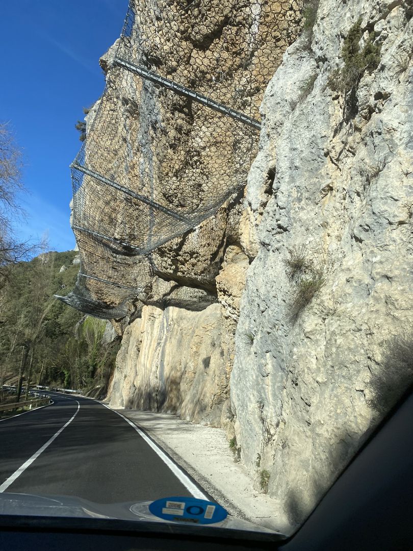 A car driving down a road next to a cliff.