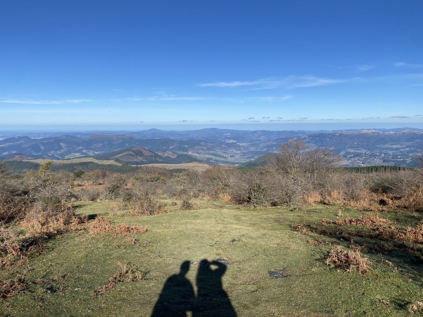 The shadow of two people standing on top of a hill.