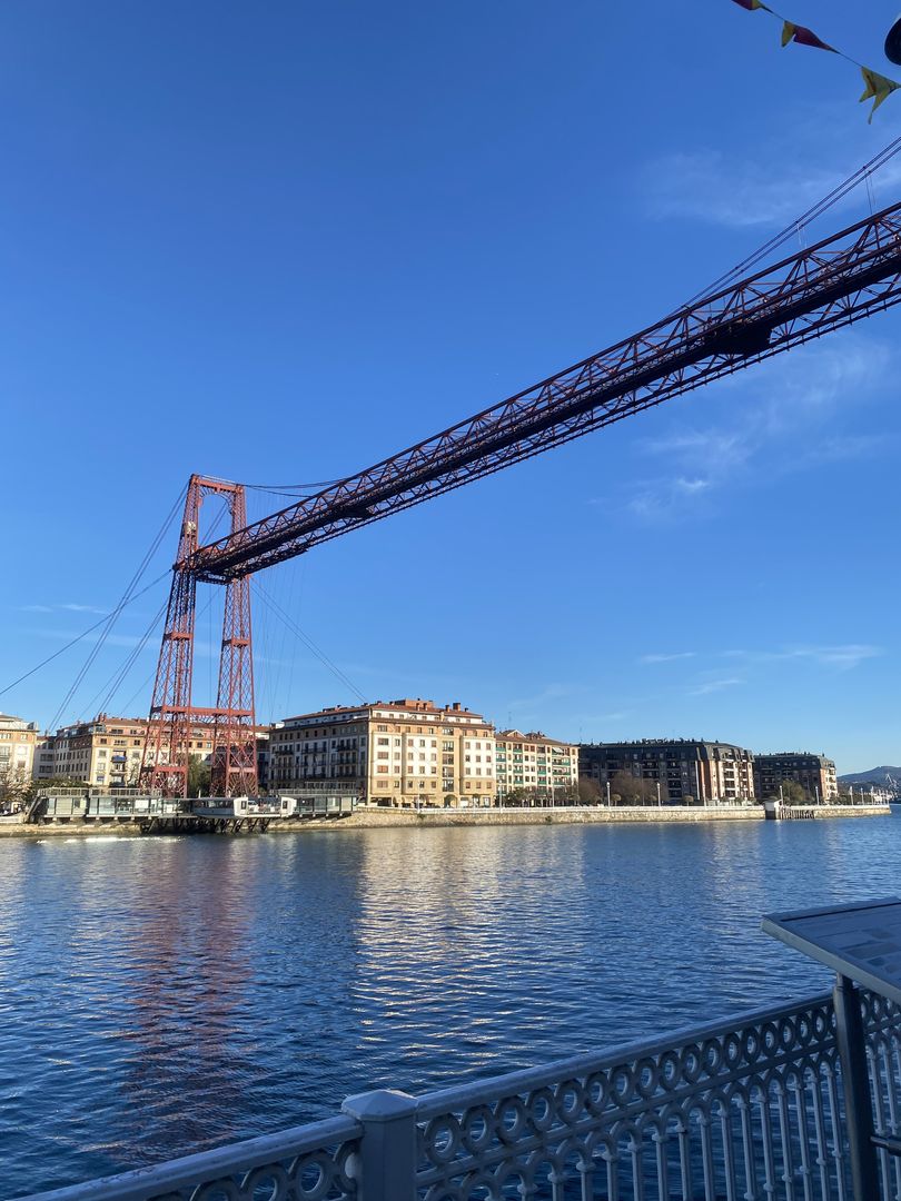 A bridge over a river with a boat in the background.