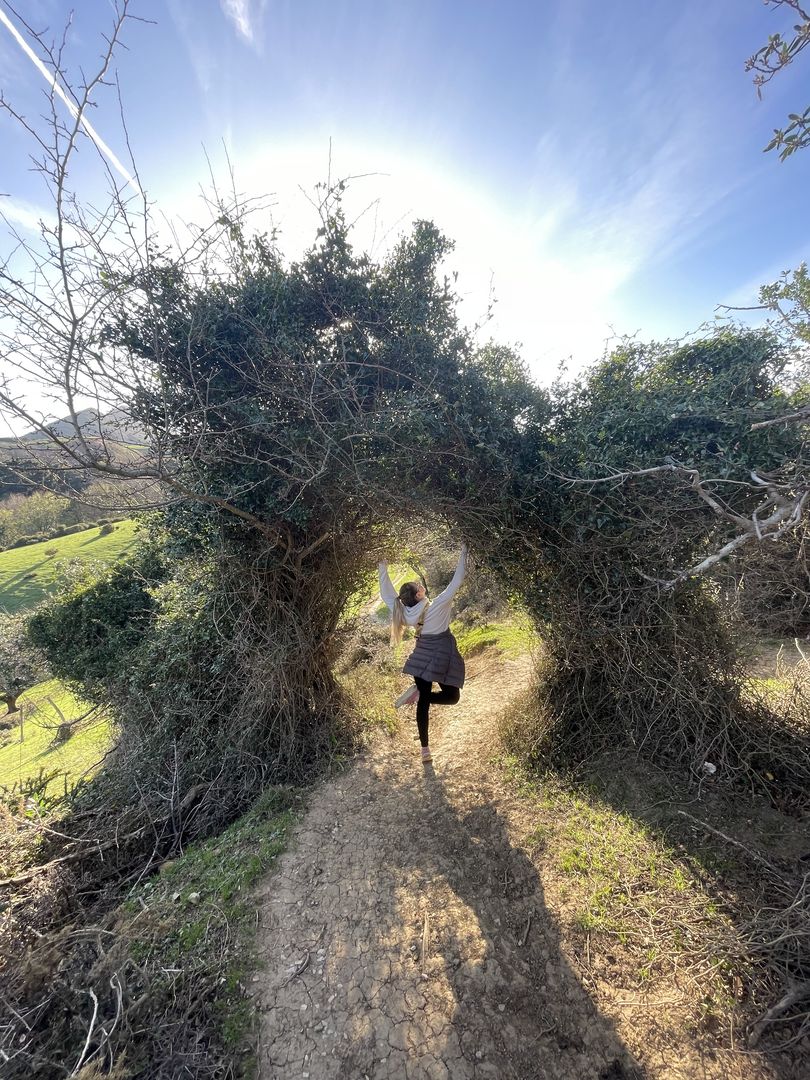 A woman is running through a tunnel of bushes.