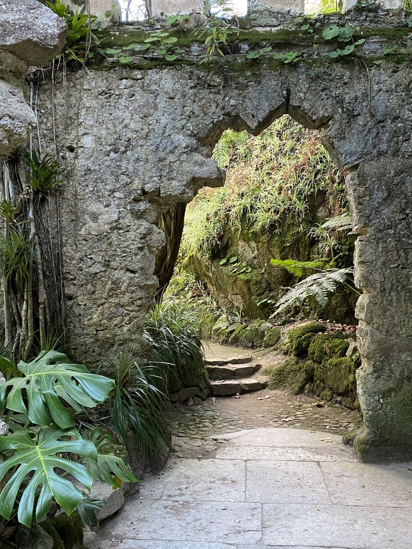A stone archway leading to a lush green garden.