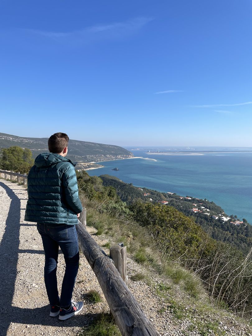 A man standing on a trail looking at the ocean.