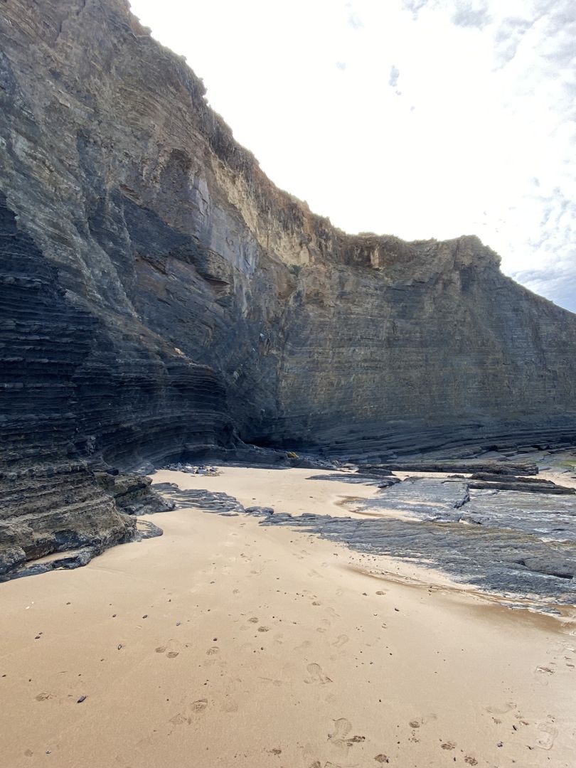 A beach with a cliff and sand next to it.