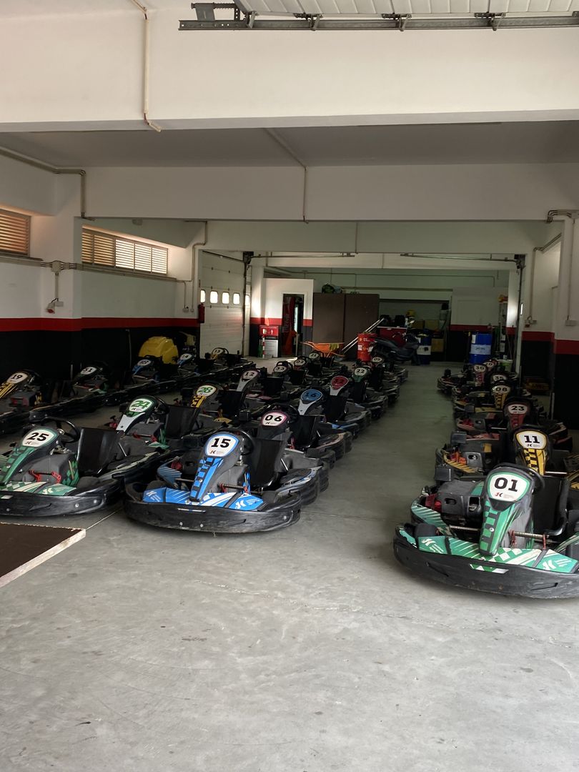 Many go - karts are lined up in a garage.