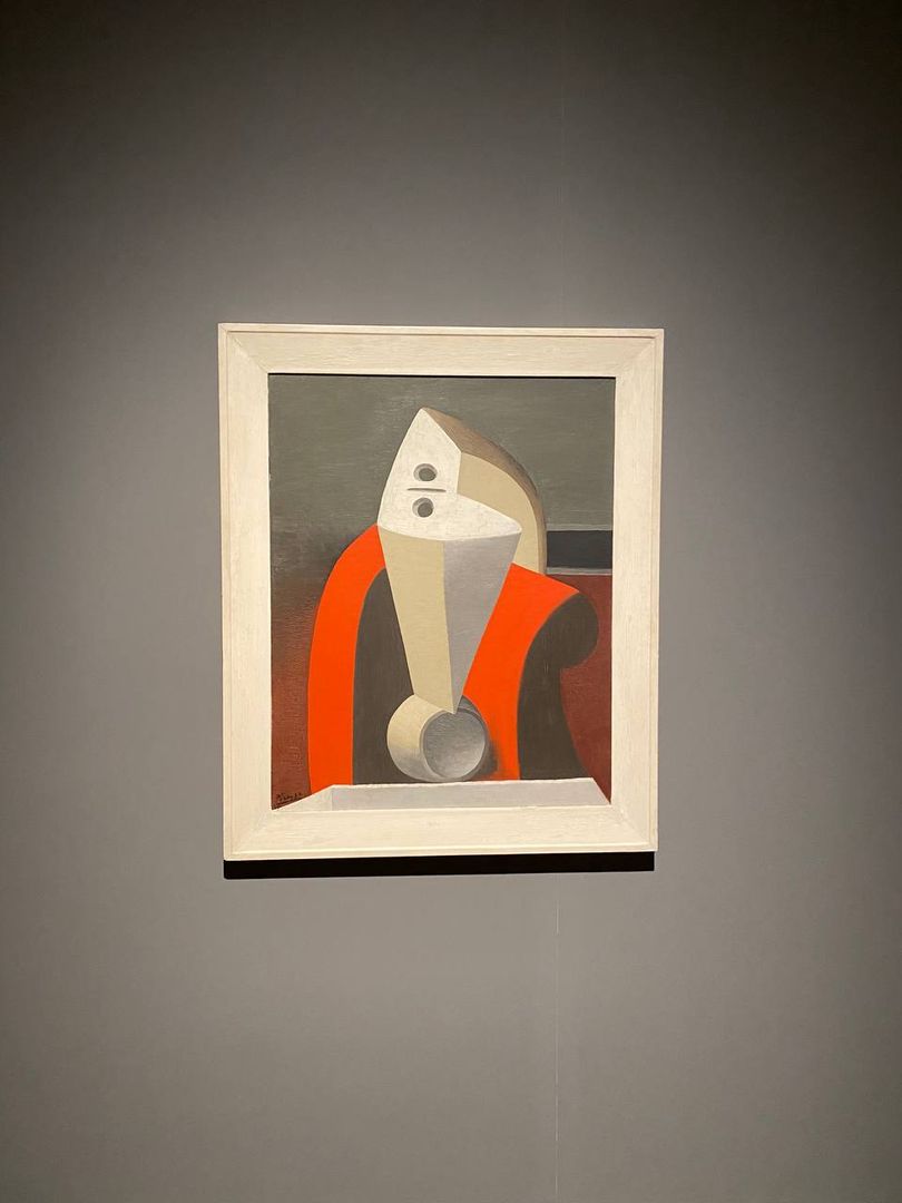A painting on a wall with a red coat on it.