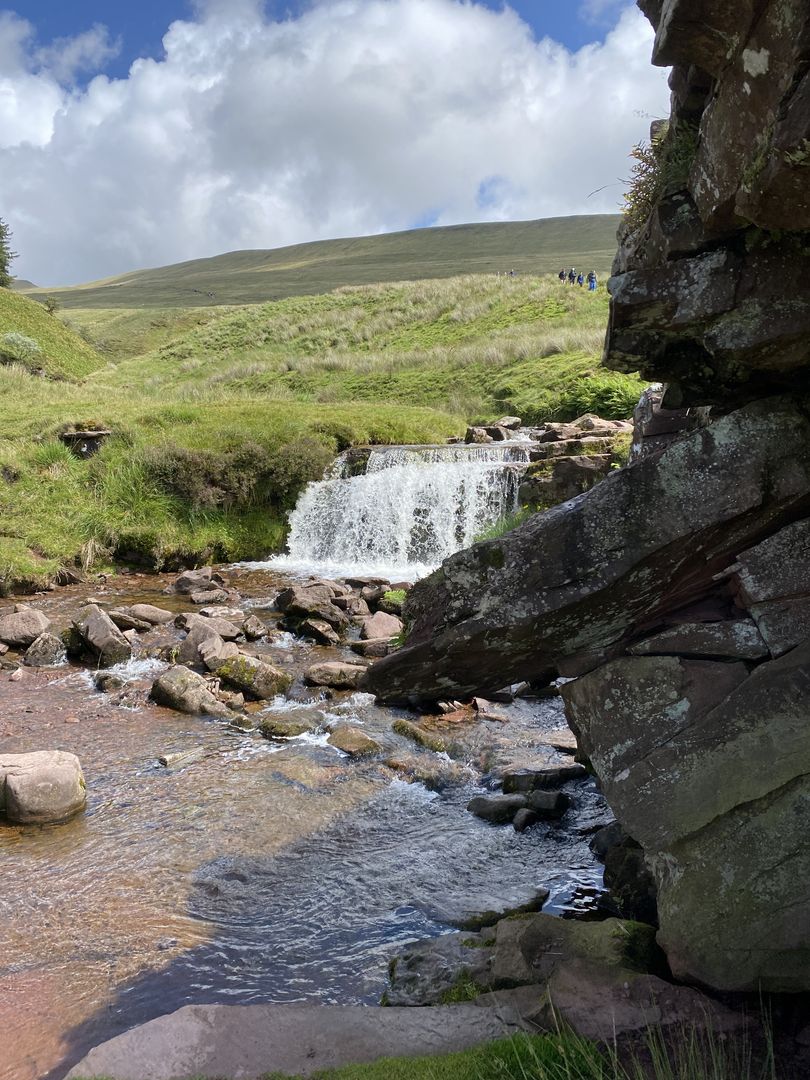 A waterfall in the middle of a grassy field.