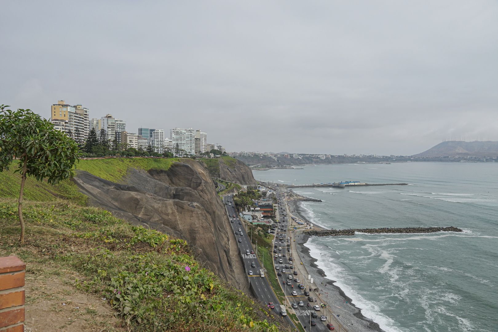 A cliff overlooking the ocean and a city.