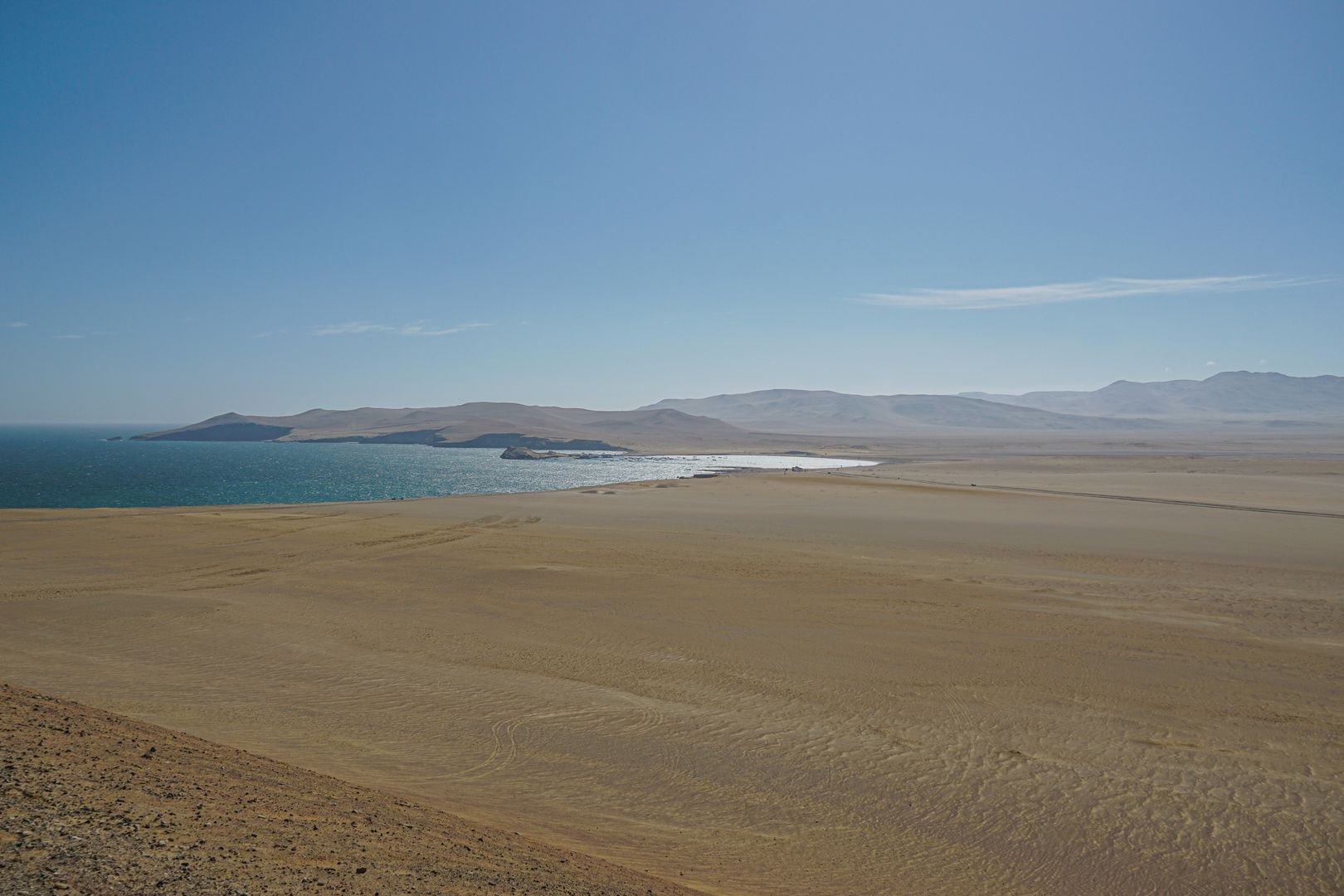A deserted beach with a blue sky and a body of water.