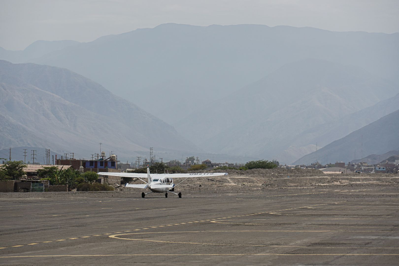 A small plane on a runway in front of mountains.
