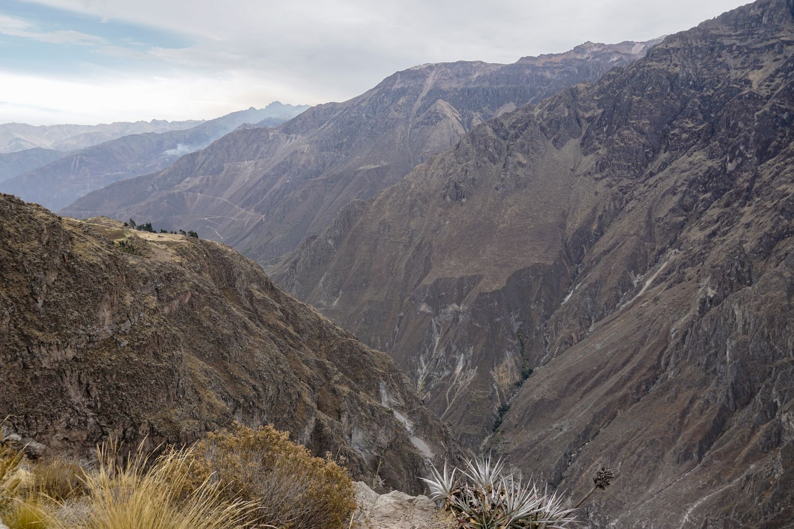 A man is standing on a cliff overlooking a valley.