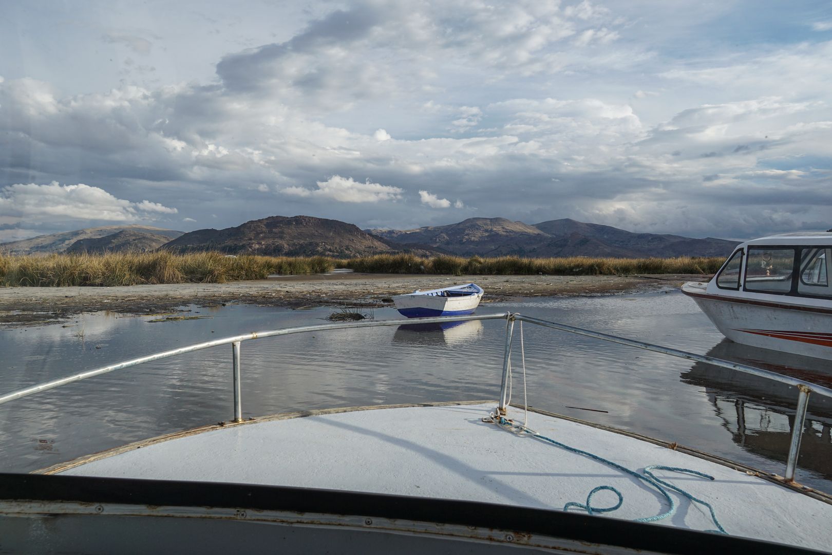A boat docked in a river with mountains in the background.