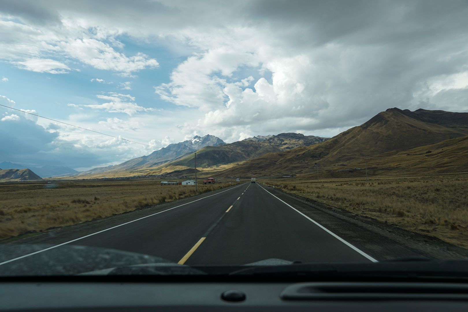 A car driving down a highway with mountains in the background.