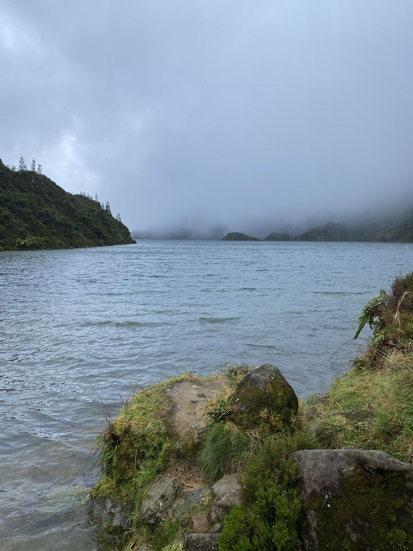 A lake surrounded by rocks and trees on a cloudy day.